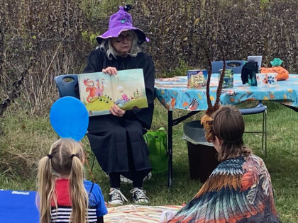 Adult in a witch costume reading a story to children